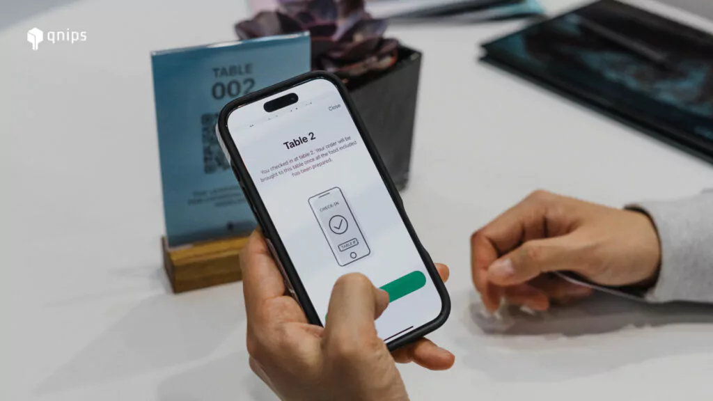 Auf dem Bild ist ein Smartphone abgebildet, das eine Person in der Hand hält. Der Bildschirm des Smartphones zeigt die Platzierung an Tisch 2.