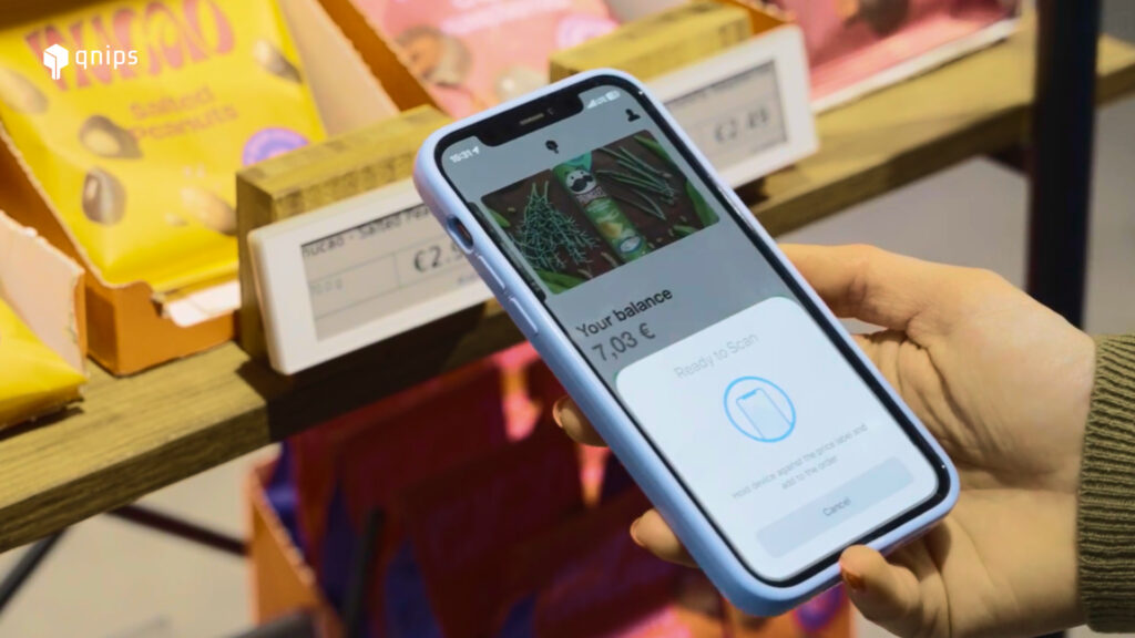 The image shows a smartphone with the qnips app open and ready to scan the digital price tag in the background.